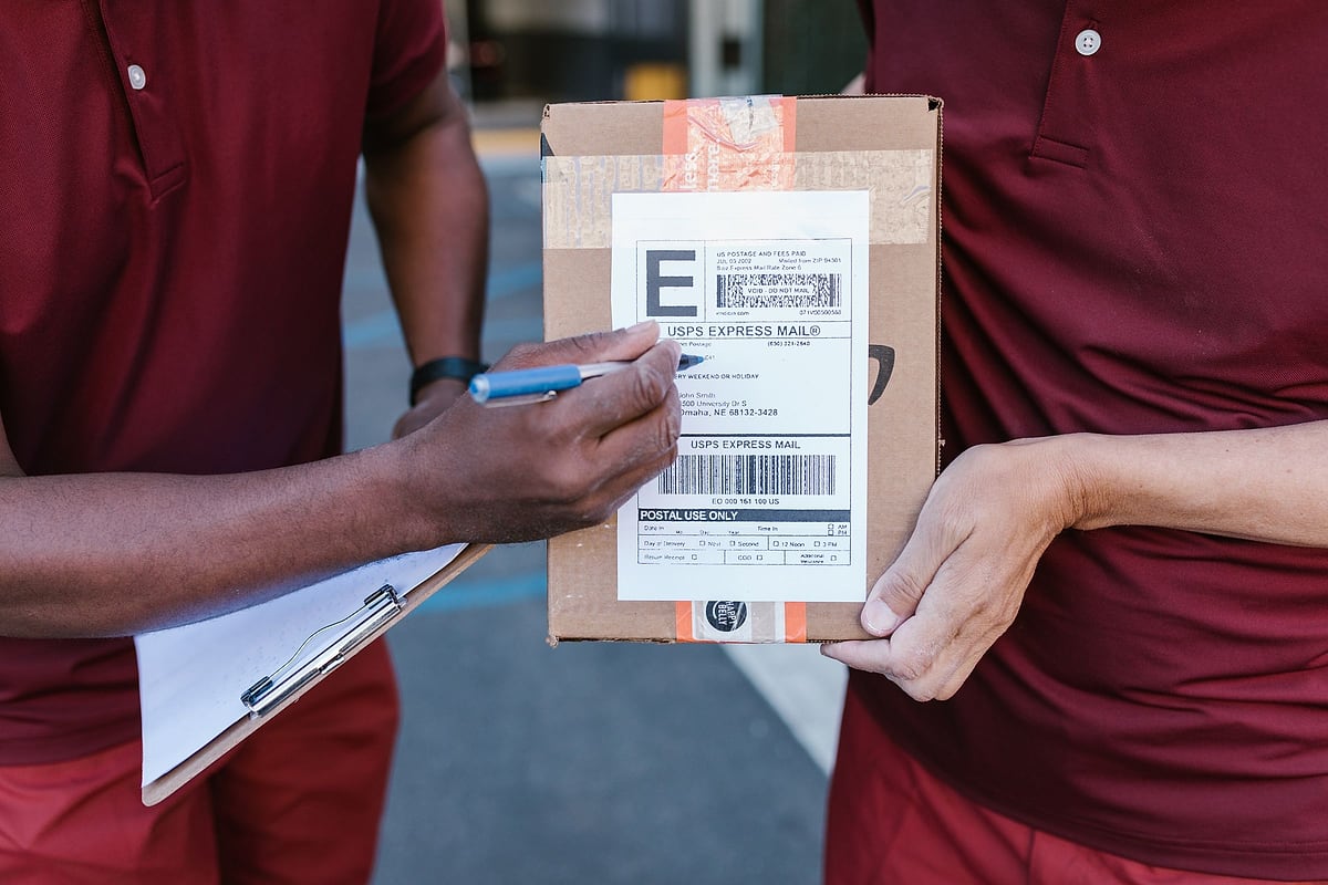 Zusteller lässt die Übergabe eines Pakets auf dem Lieferbeleg quittieren
