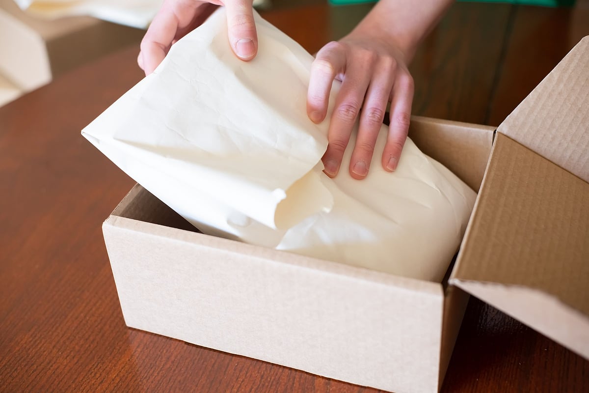 Bestellung wird mit Seidenpapier in einen Versandkarton gepackt